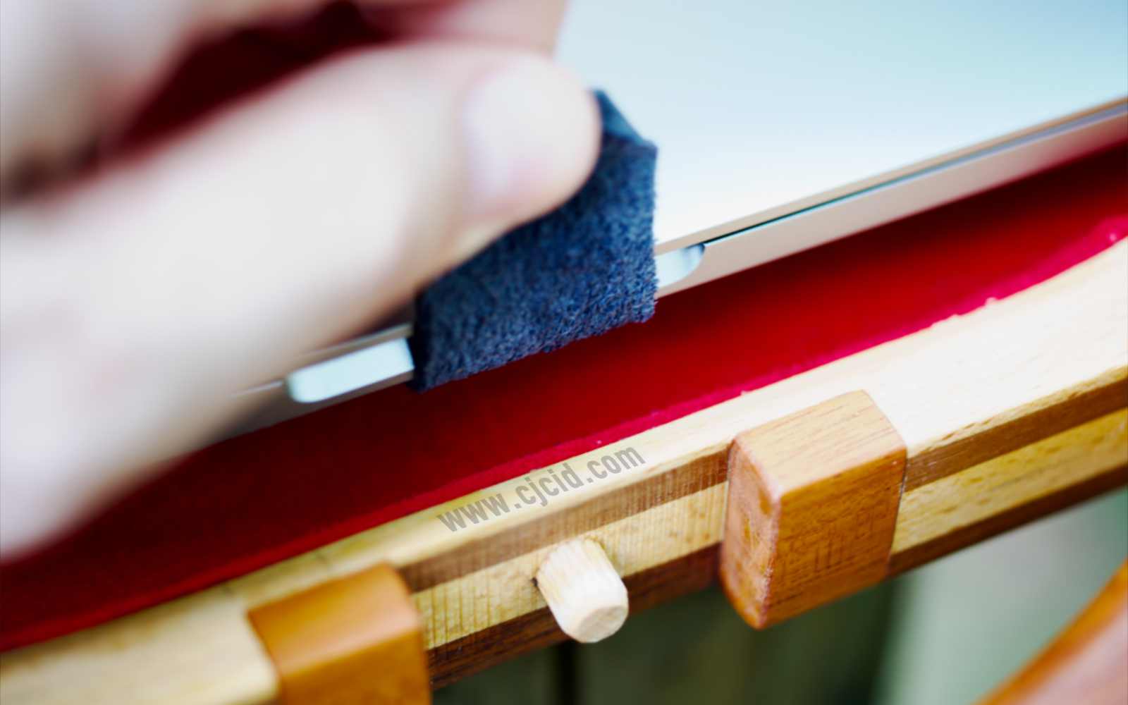 Detail view using the leather tab to remove the latop from inside, of the handcrafted solid wood attaché case for the 15″ Apple MacBook Pro