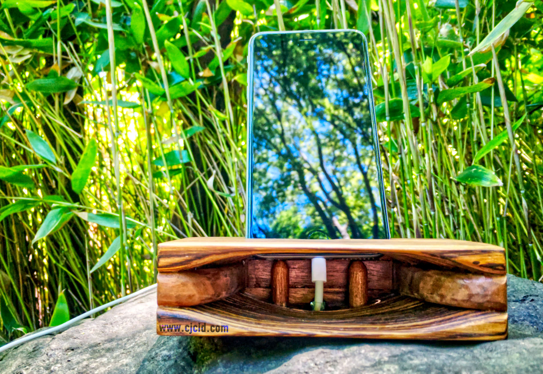 Front view of the handmade wooden iPhone stand and passive amplifier speaker “CJ Monster Mouth” with an iPhone and charging cable attached