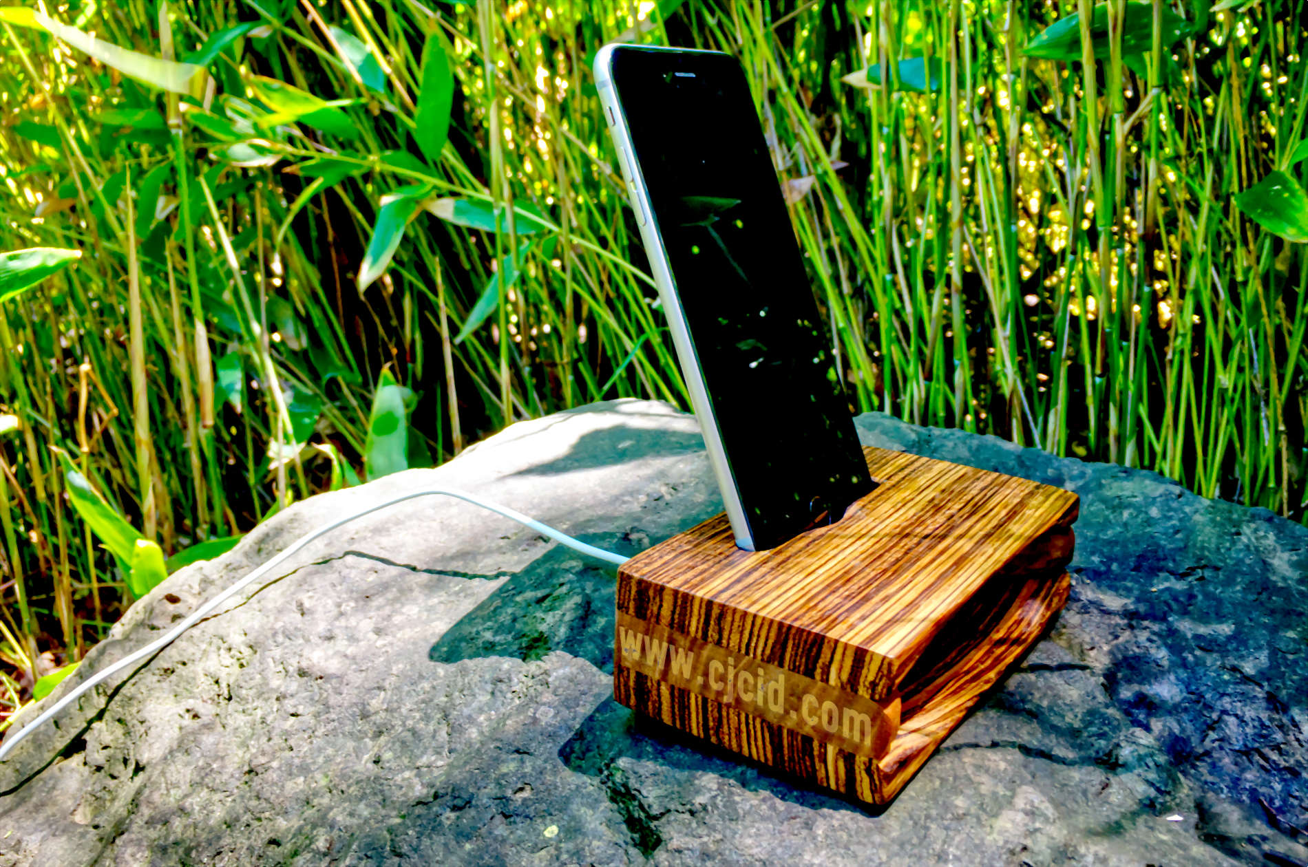 Side view of the handmade wooden iPhone stand and passive amplifier speaker “CJ Monster Mouth” with an iPhone and charging cable attached